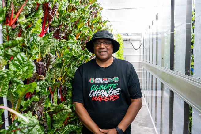 Keith Tucker smiles, posing next to a hydroponic farm.